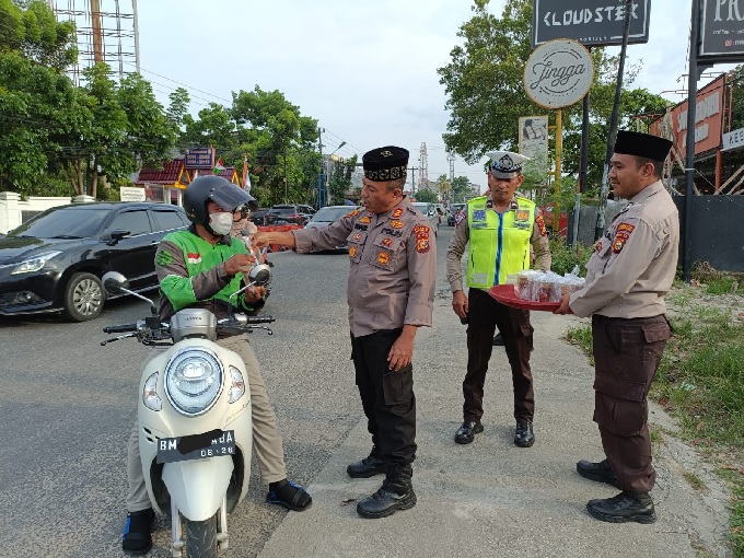 Kapolsek Bukit Raya AKP Syafnil SH berbincang dengan seorang pengendara ojol sambil memberikan takjil di Jalan Kaharuddin Nasution pada Kamis (30/3/2023) petang.